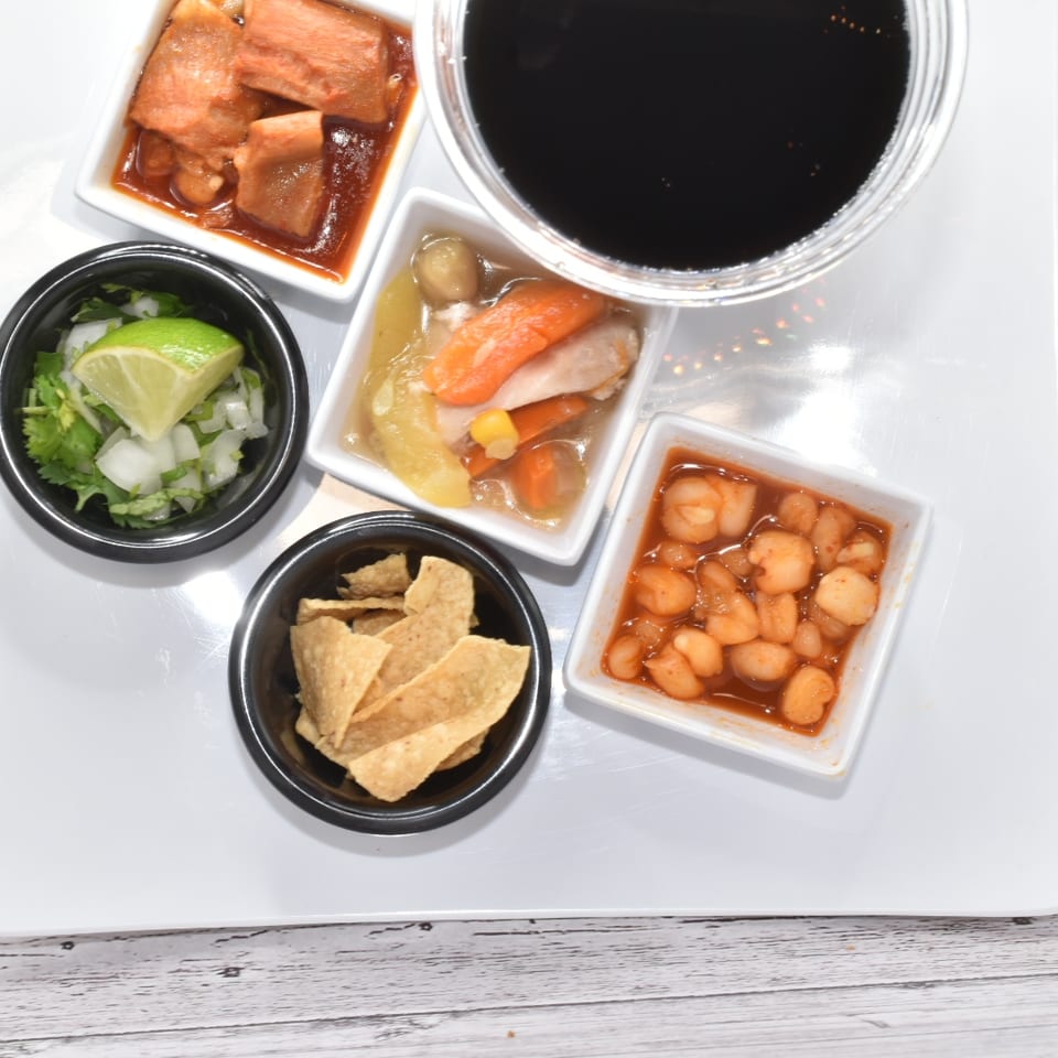 Top-down view of a white tray with various small dishes and a dark beverage.