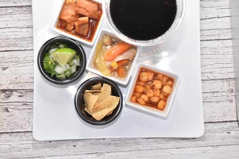 Top-down view of a white tray with various small dishes and a dark beverage.